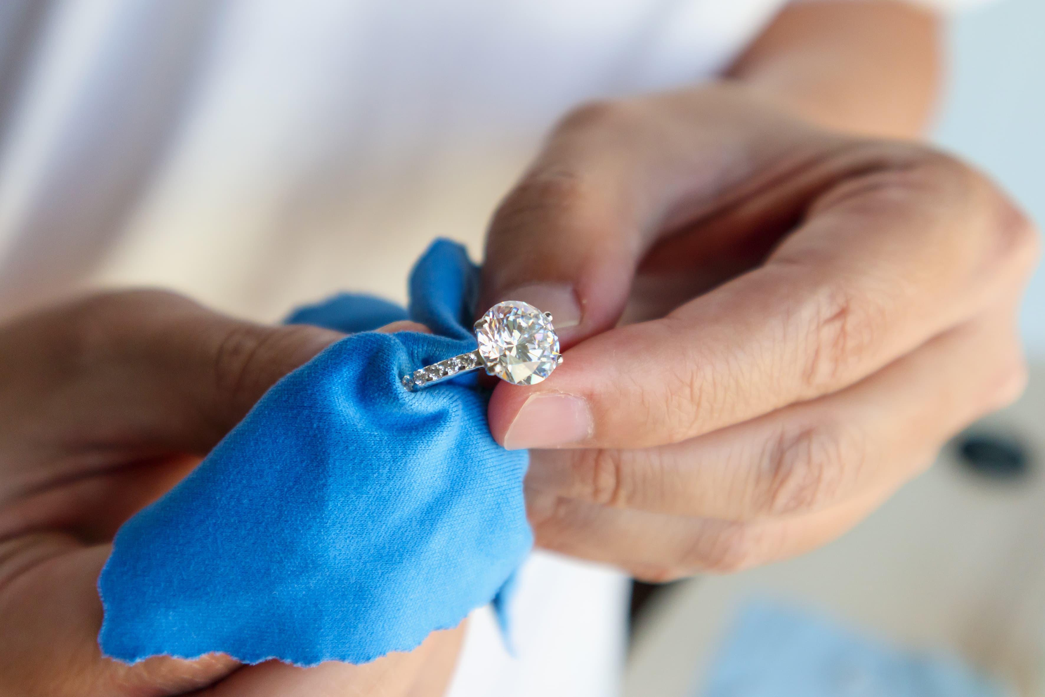 Ring, der von Hand mit einem blauen Tuch poliert wird.